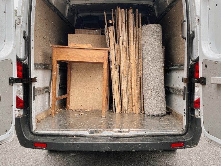 Getrennt geladener Transporter mit Holz, Spanplatten und einem Teppich