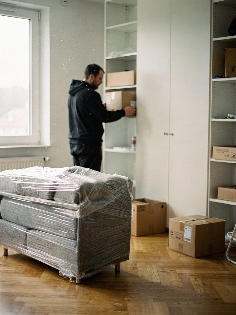 In Stretchfolie und Decken verpacktes Sofa in einer geräumten Wohnung